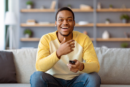 Laughing black guy watching comedy on TV at home
