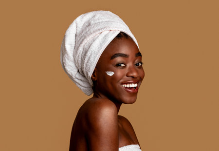 Beautiful young african american woman with cream on cheekの写真素材