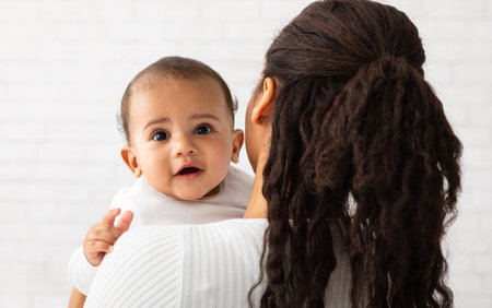 African Mom Posing With Baby Standing Back To Camera Indoorsの写真素材