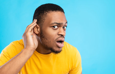 African American Guy Listening Holding Hand Near Ear, Blue Background