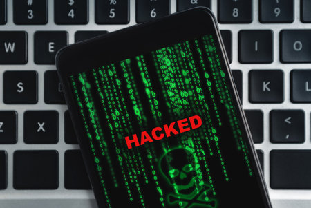 Closeup of hacked smartphone lying on laptop keyboard