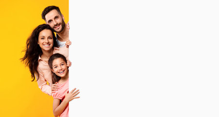 Family offer. Excited european parents and their daughter peeking out of blank white board with free space for your adの写真素材