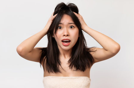 Portrait of unhappy Asian lady grabbing her headの写真素材