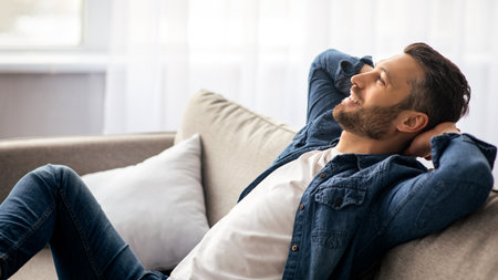 Closeup of carefree bearded man relaxing on couch at homeの写真素材