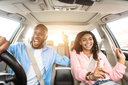 Happy black couple enjoying music driving luxury carの写真素材