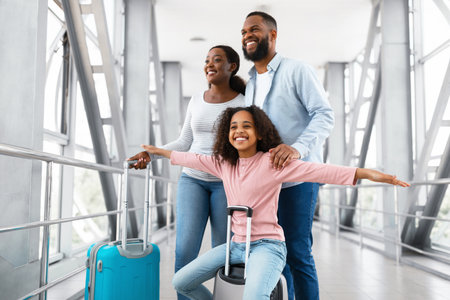 Happy black family traveling with kid, walking in airportの写真素材