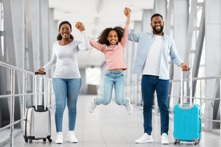 Happy black family traveling with daughter, having fun in airportの写真素材