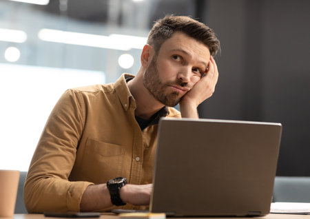 Unhappy Businessman Sitting Near Laptop Thinking Sitting In Office