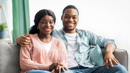 Loving black couple sitting on sofa in living roomの写真素材