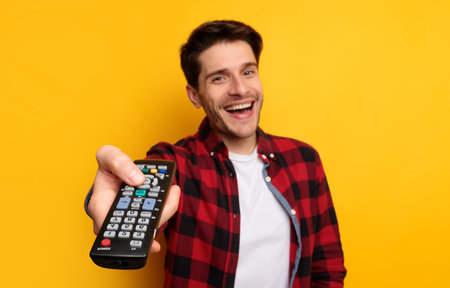 Young handsome guy watching tv holding remote controlの写真素材