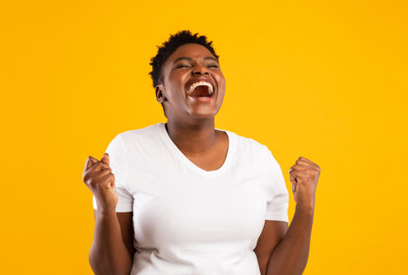 Joyful Black Woman Shouting Shaking Fists Posing Over Yellow Background