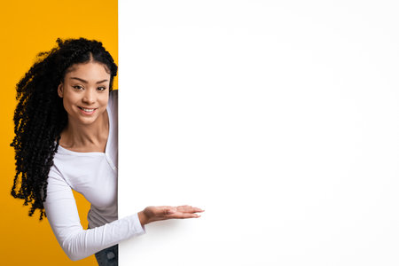 Look At This. Smiling Young Black Lady Pointing At White Advertisement Boardの写真素材