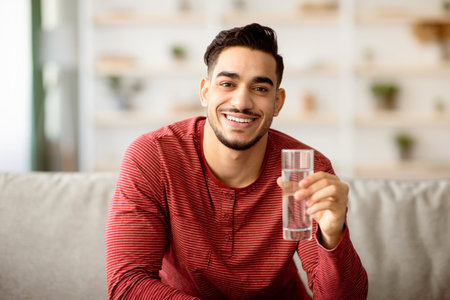 Happy arab guy drinking water at homeの写真素材