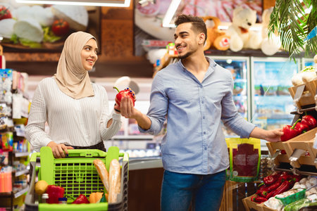 Muslim Family Couple On Grocery Shopping Choosing Vegetables In Supermarketの写真素材