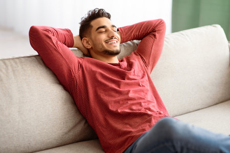 Happy middle-eastern guy in casual chilling at homeの写真素材