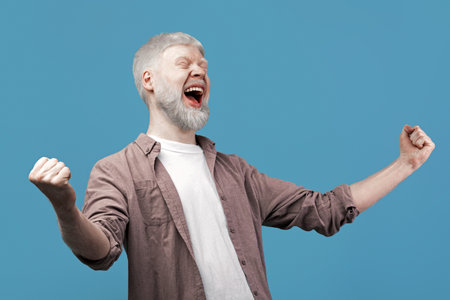 Achievement concept. Overjoyed albino man cheering and screaming, celebrating victory, blue background with free spaceの写真素材