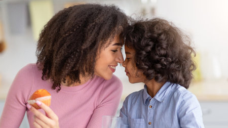 Cute Little Afro Girl And Woman Having Breakfast In Kitchenの写真素材
