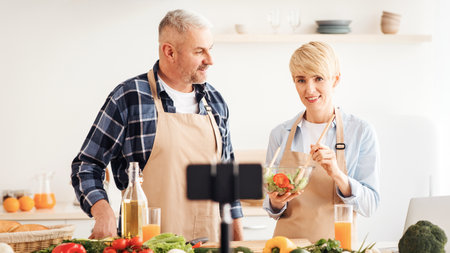 Couple cook together, explain recipe and record video for vlog and social media with smartphone camera and tripodの写真素材