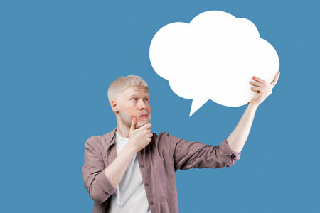 Thinking concept. Albino guy with speech bubble deep in thought posing on color background, space...