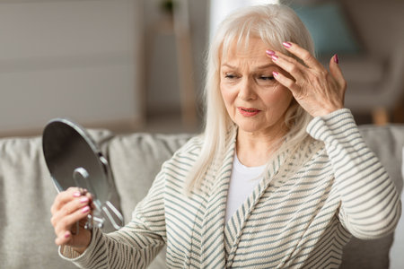 Adult woman checking her face in mirror, touching face