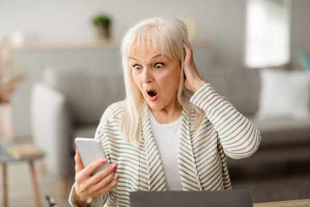 Surprised shocked mature woman using cell phone