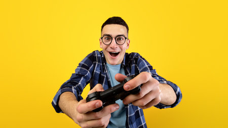 Happy Caucasian guy with joystick playing video game on orange studio background. Stay home hobbies...
