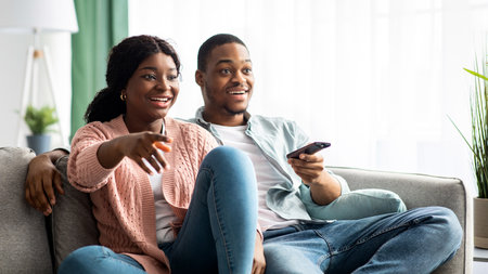 Happy african american family watching TV together at home