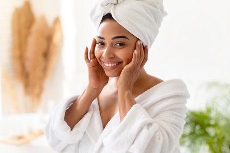 Pretty African American Lady Touching Face Smiling Posing In Bathroomの写真素材