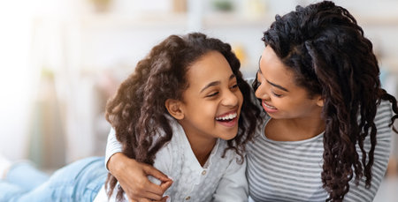 Joyful black girl reading book with her momの写真素材