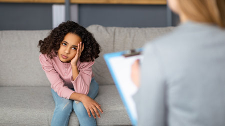 Female child psychologist working with upset black girl, teenager patient talking about her feelingsの写真素材