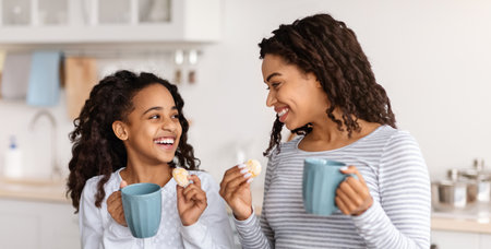 Cute black mother and daughter drinking tea with cookiesの写真素材
