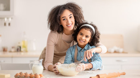 Positive black woman and daughter kneading dough in modern kitchenの写真素材