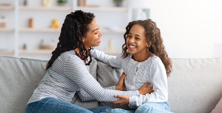 Cheerful black mother and daughter having fun together at homeの写真素材