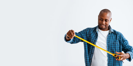 Carpenter, handyman, construction with tape-line. Happy african american man holding measuring tape,...