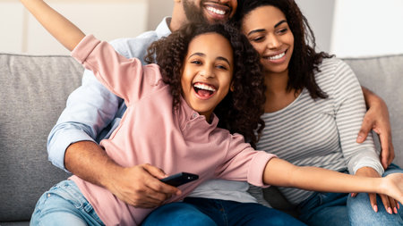Happy young family watching television sitting on sofaの写真素材