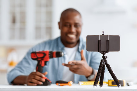 Carpenter blogger recording video review of instruments on phone, showing modern electric drill, selective focusの写真素材