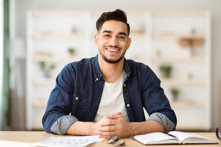 Cheerful arab guy in casual sitting at workdeskの写真素材