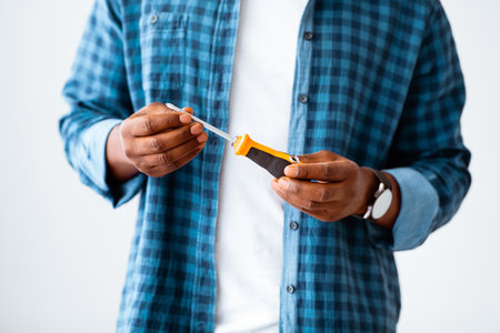 Caucasian male hand holding a red plastic handle screwdriver isolated on gray background.の写真素材