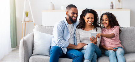 Happy african american family holding and using smartphone