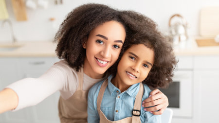 Cheerful african american mom taking selfie with cute daughterの写真素材