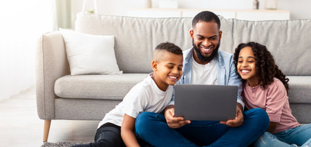 Happy african american family using laptop in living roomの写真素材
