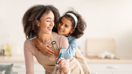 Happy black woman and child daughter mixing doughの写真素材