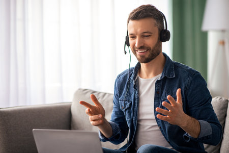 Cheerful bearded man having video conference with colleagues from homeの写真素材