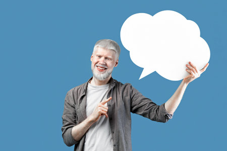 Excited young albino man pointing at empty speech bubble, standing over blue studio background, mockup for designの写真素材