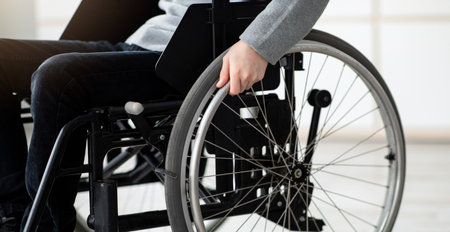 Cropped view of impaired teen boy sitting in wheelchair at home, copy space. Disability in adolescents conceptの写真素材