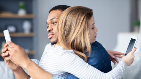 Gadget Addiction Concept. Black Man And White Woman Using Smartphones While Huggingの写真素材