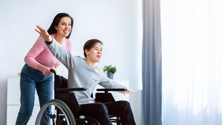 Young mother and her disabled son in wheelchair having fun, playing together at homeの写真素材
