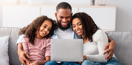 Happy black family using laptop in living roomの写真素材