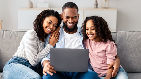 Happy African American family using laptop sitting on the couchの写真素材