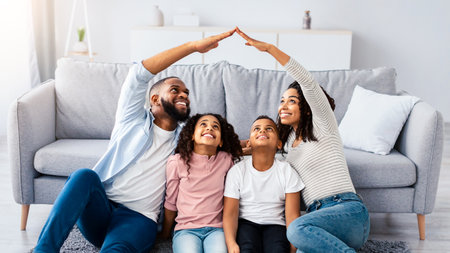 Black parents making symbolic roof of hands above childrenの写真素材